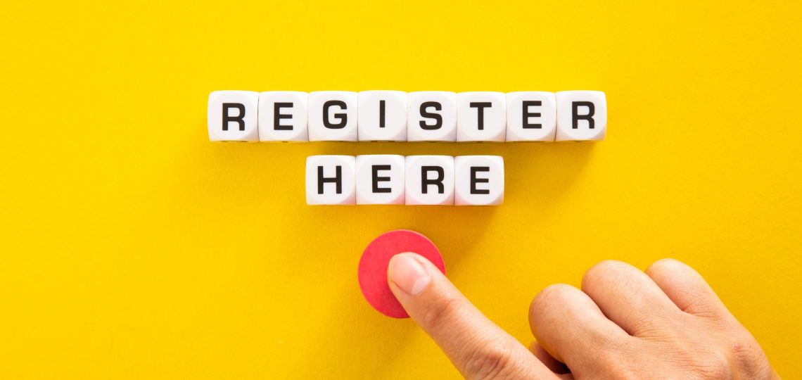 Hand pushing button with Register Here word on yellow background